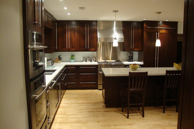 Inspiration for a large contemporary l-shaped light wood floor enclosed kitchen remodel in Salt Lake City with a double-bowl sink, shaker cabinets, dark wood cabinets, quartz countertops, white backsplash, glass tile backsplash, paneled appliances and an island