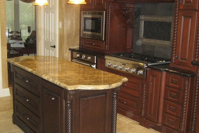 ヒューストンにある中くらいなトラディショナルスタイルのおしゃれなキッチン (レイズドパネル扉のキャビネット、中間色木目調キャビネット、御影石カウンター、シルバーの調理設備) の写真