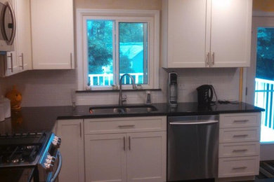 Foto de cocina moderna de tamaño medio con puertas de armario blancas, encimera de granito, salpicadero de azulejos tipo metro, electrodomésticos de acero inoxidable y suelo de pizarra