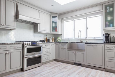 Example of a mid-sized minimalist l-shaped porcelain tile and beige floor eat-in kitchen design in Dallas with recessed-panel cabinets, gray cabinets, granite countertops, white backsplash, glass tile backsplash, stainless steel appliances and a farmhouse sink