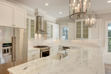 Mid-sized transitional l-shaped light wood floor open concept kitchen photo in Other with a farmhouse sink, recessed-panel cabinets, white cabinets, marble countertops, white backsplash, porcelain backsplash, stainless steel appliances and an island