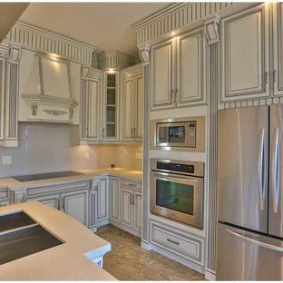 This is an example of a large asian u-shaped eat-in kitchen in Vancouver with an undermount sink, beige cabinets, quartzite benchtops, white splashback, glass sheet splashback, stainless steel appliances, marble floors and with island.