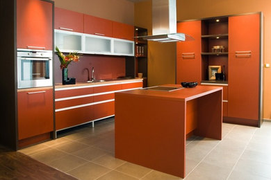 フェニックスにある高級な中くらいなコンテンポラリースタイルのおしゃれなキッチン (ダブルシンク、フラットパネル扉のキャビネット、オレンジのキャビネット、人工大理石カウンター、シルバーの調理設備、磁器タイルの床) の写真