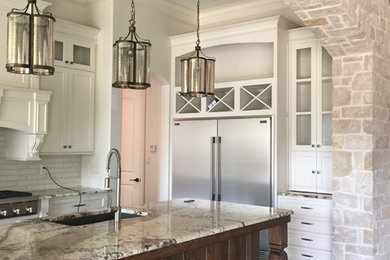 Example of a classic l-shaped concrete floor kitchen design in Dallas with an undermount sink, granite countertops, white backsplash, stainless steel appliances and an island