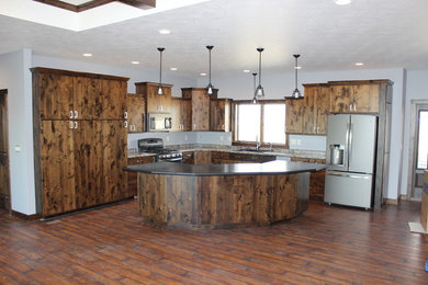 Example of a large mountain style u-shaped dark wood floor open concept kitchen design in Other with a drop-in sink, flat-panel cabinets, dark wood cabinets, granite countertops and stainless steel appliances