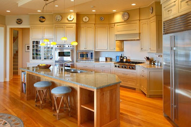 Example of a large trendy medium tone wood floor kitchen design in Bridgeport with a double-bowl sink, recessed-panel cabinets, beige cabinets, granite countertops, stainless steel appliances and an island