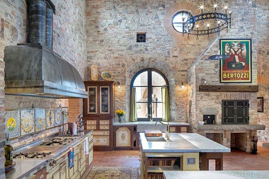 Inspiration for a huge mediterranean l-shaped terra-cotta tile and brown floor open concept kitchen remodel in Austin with an undermount sink, recessed-panel cabinets, medium tone wood cabinets, stainless steel countertops, beige backsplash, stone tile backsplash and two islands