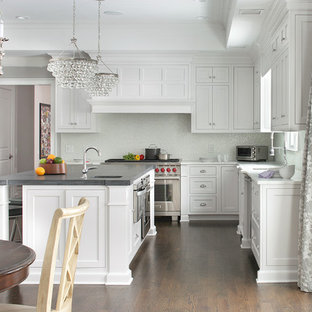 Inspiration for a traditional u-shaped kitchen/diner in New York with shaker cabinets, white cabinets, white splashback, stainless steel appliances, dark hardwood flooring and an island.