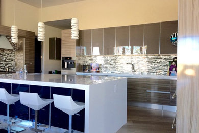 Eat-in kitchen - large contemporary u-shaped limestone floor eat-in kitchen idea in Las Vegas with an undermount sink, glass-front cabinets, gray cabinets, quartz countertops, gray backsplash, glass tile backsplash, stainless steel appliances and an island