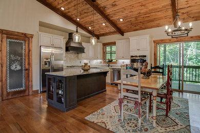 Cottage chic l-shaped medium tone wood floor eat-in kitchen photo in Charlotte with white cabinets, granite countertops and an island