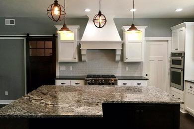 Inspiration for a large transitional u-shaped dark wood floor and brown floor open concept kitchen remodel in Other with an undermount sink, shaker cabinets, white cabinets, solid surface countertops, gray backsplash, porcelain backsplash, stainless steel appliances, an island and black countertops