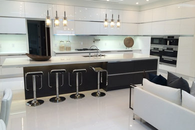 Example of a large minimalist u-shaped eat-in kitchen design in Los Angeles with flat-panel cabinets and an island