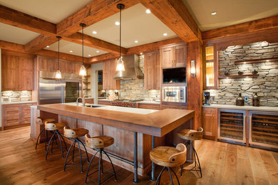 Example of a large mountain style l-shaped medium tone wood floor and brown floor eat-in kitchen design in Calgary with an undermount sink, shaker cabinets, medium tone wood cabinets, gray backsplash, stone tile backsplash, stainless steel appliances and an island