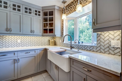 Enclosed kitchen - mid-sized cottage l-shaped enclosed kitchen idea in Calgary with a farmhouse sink, shaker cabinets, gray cabinets, granite countertops, white backsplash, porcelain backsplash, stainless steel appliances, an island and white countertops