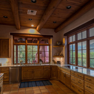 Ejemplo de cocina de estilo americano, cerrada, sin isla, con fregadero de tres senos, armarios con paneles empotrados, puertas de armario marrones, encimera de granito, electrodomésticos de acero inoxidable, suelo de baldosas de terracota y suelo rosa