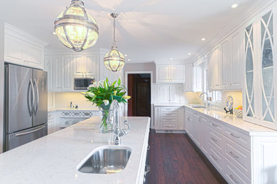 Example of a large farmhouse l-shaped medium tone wood floor and brown floor eat-in kitchen design in Toronto with an undermount sink, raised-panel cabinets, white cabinets, quartz countertops, white backsplash, stainless steel appliances, subway tile backsplash and an island