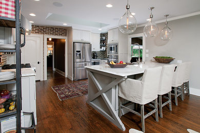 Example of a transitional u-shaped dark wood floor eat-in kitchen design in Atlanta with a farmhouse sink, shaker cabinets, gray cabinets, marble countertops, brown backsplash and stainless steel appliances