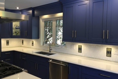 Inspiration for a mid-sized modern open concept kitchen remodel in Vancouver with a double-bowl sink, blue cabinets, quartzite countertops, white backsplash, stone tile backsplash, stainless steel appliances and an island