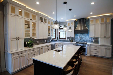 Inspiration for a huge timeless l-shaped medium tone wood floor and brown floor enclosed kitchen remodel in New York with an undermount sink, flat-panel cabinets, white cabinets, quartz countertops, metallic backsplash, ceramic backsplash, stainless steel appliances, an island and white countertops