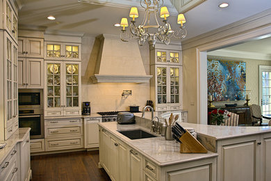 Example of a large classic l-shaped dark wood floor eat-in kitchen design in Detroit with a single-bowl sink, glass-front cabinets, white cabinets, marble countertops, white backsplash, stone slab backsplash, stainless steel appliances and an island