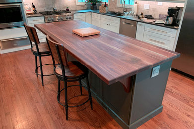Пример оригинального дизайна: большая параллельная кухня в современном стиле с обеденным столом, монолитной мойкой, деревянной столешницей, техникой из нержавеющей стали, паркетным полом среднего тона, островом и коричневой столешницей