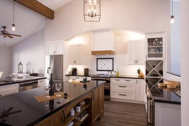 サンタバーバラにある高級な広いインダストリアルスタイルのおしゃれなキッチン (白いキャビネット、白いキッチンパネル、シルバーの調理設備、無垢フローリング、茶色い床、黒いキッチンカウンター) の写真