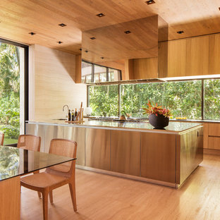 Inspiration for a tropical light wood floor kitchen remodel in Miami with flat-panel cabinets, light wood cabinets, window backsplash, an island and stainless steel countertops