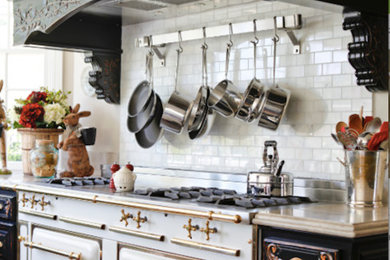 ロサンゼルスにあるトラディショナルスタイルのおしゃれなキッチン (レイズドパネル扉のキャビネット、黒いキャビネット、ライムストーンカウンター、白いキッチンパネル、サブウェイタイルのキッチンパネル、白い調理設備、無垢フローリング) の写真