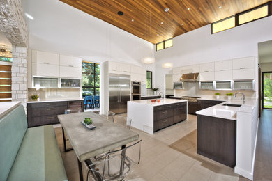 Inspiration for an expansive contemporary u-shaped kitchen/diner in Sacramento with a submerged sink, flat-panel cabinets, white cabinets, engineered stone countertops, white splashback, glass sheet splashback, stainless steel appliances, ceramic flooring, an island, beige floors and white worktops.