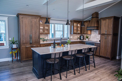 Mid-sized elegant l-shaped vinyl floor, gray floor and vaulted ceiling open concept kitchen photo in Milwaukee with an undermount sink, recessed-panel cabinets, medium tone wood cabinets, quartz countertops, beige backsplash, porcelain backsplash, paneled appliances, an island and white countertops