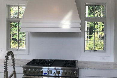 クリーブランドにあるトランジショナルスタイルのおしゃれなキッチン (白いキャビネット、クオーツストーンカウンター、シルバーの調理設備、白いキッチンカウンター) の写真