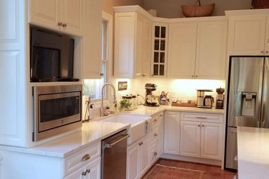 ナッシュビルにあるお手頃価格の中くらいなコンテンポラリースタイルのおしゃれなキッチン (エプロンフロントシンク、レイズドパネル扉のキャビネット、白いキャビネット、珪岩カウンター、白いキッチンパネル、セラミックタイルのキッチンパネル、シルバーの調理設備、無垢フローリング、茶色い床、白いキッチンカウンター、塗装板張りの天井) の写真