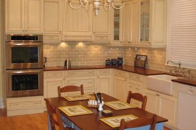 Inspiration for a large transitional u-shaped medium tone wood floor enclosed kitchen remodel in Montreal with a drop-in sink, recessed-panel cabinets, white cabinets, beige backsplash, subway tile backsplash, stainless steel appliances and no island