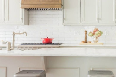 Inspiration for a timeless kitchen remodel in Boston with recessed-panel cabinets, white cabinets, marble countertops, white backsplash, subway tile backsplash, stainless steel appliances and an island