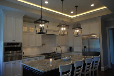 Example of a large classic l-shaped eat-in kitchen design in Other with a farmhouse sink, glass-front cabinets, white cabinets, granite countertops, white backsplash, ceramic backsplash, stainless steel appliances and an island
