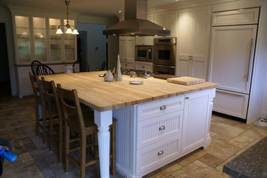 ポートランドにあるおしゃれなキッチン (ルーバー扉のキャビネット、白いキャビネット、木材カウンター、パネルと同色の調理設備、セラミックタイルの床) の写真
