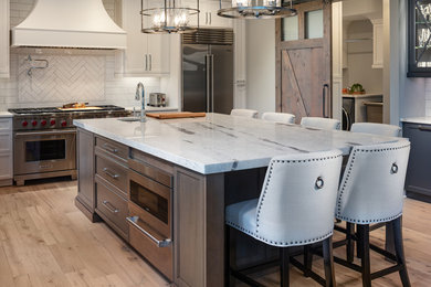 Eat-in kitchen - mid-sized transitional light wood floor and brown floor eat-in kitchen idea in Atlanta with a farmhouse sink, shaker cabinets, white cabinets, quartzite countertops, white backsplash, subway tile backsplash, stainless steel appliances, an island and white countertops