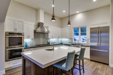 Inspiration for a mid-sized transitional u-shaped porcelain tile and brown floor open concept kitchen remodel in San Diego with a farmhouse sink, recessed-panel cabinets, white cabinets, quartz countertops, gray backsplash, stainless steel appliances, an island, ceramic backsplash and white countertops
