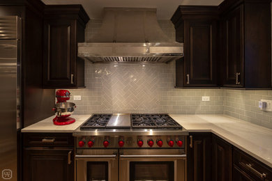 シカゴにある高級な中くらいなトランジショナルスタイルのおしゃれなキッチン (エプロンフロントシンク、レイズドパネル扉のキャビネット、濃色木目調キャビネット、珪岩カウンター、グレーのキッチンパネル、磁器タイルのキッチンパネル、シルバーの調理設備、無垢フローリング、茶色い床、マルチカラーのキッチンカウンター) の写真