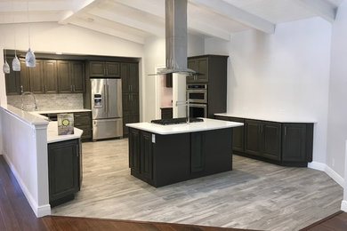 Open concept kitchen - large modern u-shaped porcelain tile and gray floor open concept kitchen idea in Tampa with raised-panel cabinets, gray cabinets, solid surface countertops, gray backsplash, stone tile backsplash, stainless steel appliances and an island