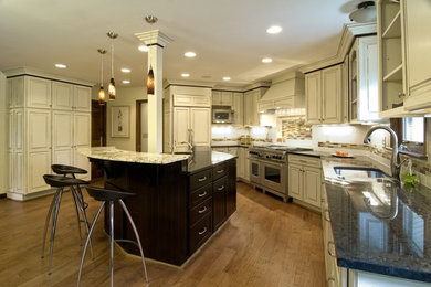 Example of a transitional u-shaped medium tone wood floor eat-in kitchen design in Columbus with a double-bowl sink, raised-panel cabinets, beige cabinets, granite countertops, multicolored backsplash, ceramic backsplash, stainless steel appliances and an island