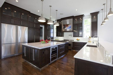 Large trendy u-shaped medium tone wood floor kitchen photo in Chicago with an undermount sink, shaker cabinets, dark wood cabinets, solid surface countertops, white backsplash, porcelain backsplash, stainless steel appliances and an island