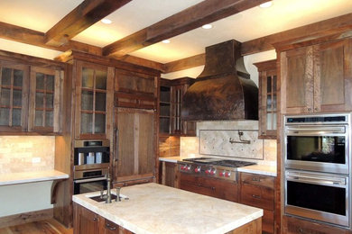 Inspiration for a mid-sized craftsman medium tone wood floor eat-in kitchen remodel in Other with a farmhouse sink, dark wood cabinets, marble countertops, beige backsplash, stone tile backsplash, stainless steel appliances and an island