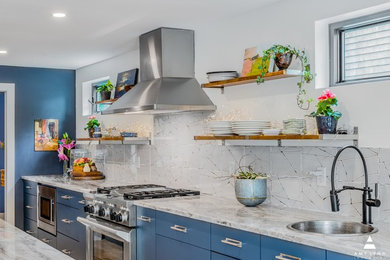 Example of a large minimalist l-shaped light wood floor eat-in kitchen design in Boston with a farmhouse sink, flat-panel cabinets, blue cabinets, quartzite countertops, white backsplash, porcelain backsplash, stainless steel appliances, an island and white countertops