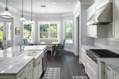 Open concept kitchen - large transitional l-shaped dark wood floor open concept kitchen idea in Tampa with a farmhouse sink, recessed-panel cabinets, white cabinets, marble countertops, white backsplash, subway tile backsplash, stainless steel appliances and an island