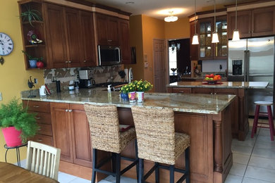 This is an example of a medium sized traditional l-shaped kitchen/diner in Cedar Rapids with medium wood cabinets, stainless steel appliances, ceramic flooring and multiple islands.