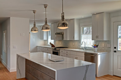 Eat-in kitchen - large contemporary galley medium tone wood floor and brown floor eat-in kitchen idea in New York with an undermount sink, shaker cabinets, white cabinets, marble countertops, stainless steel appliances, an island, white backsplash, subway tile backsplash and white countertops