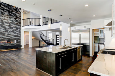 Example of a large trendy l-shaped dark wood floor open concept kitchen design in Kansas City with a single-bowl sink, flat-panel cabinets, white cabinets, quartzite countertops, white backsplash, glass tile backsplash, stainless steel appliances and an island