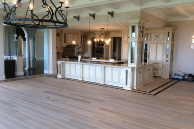 Large elegant u-shaped light wood floor and beige floor eat-in kitchen photo in Miami with raised-panel cabinets, light wood cabinets, stainless steel appliances, an island, a drop-in sink and granite countertops