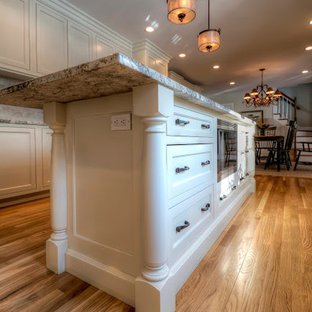 Large elegant u-shaped light wood floor and brown floor eat-in kitchen photo in Boston with an undermount sink, beaded inset cabinets, white cabinets, granite countertops, beige backsplash, stainless steel appliances, an island and stone tile backsplash